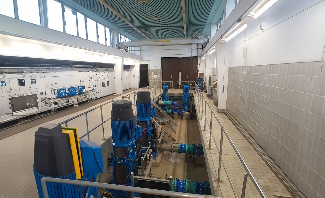 Browne Group - Large blue industrial pumps and pipes in a clean, well-lit facility with tiled walls and a metal railing.