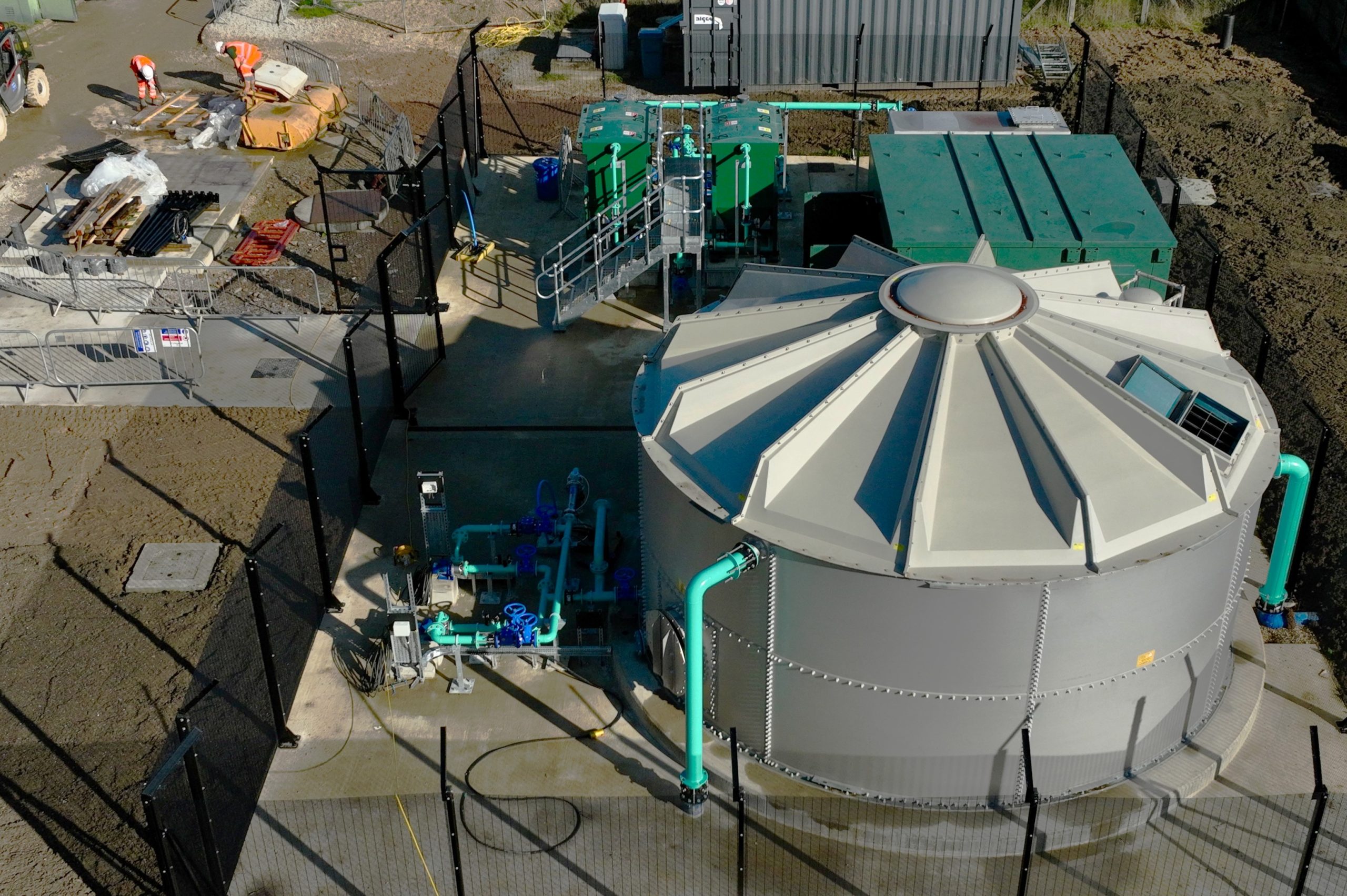 Browne Group - Aerial view of a water treatment facility with large tanks, piping, and workers on site.