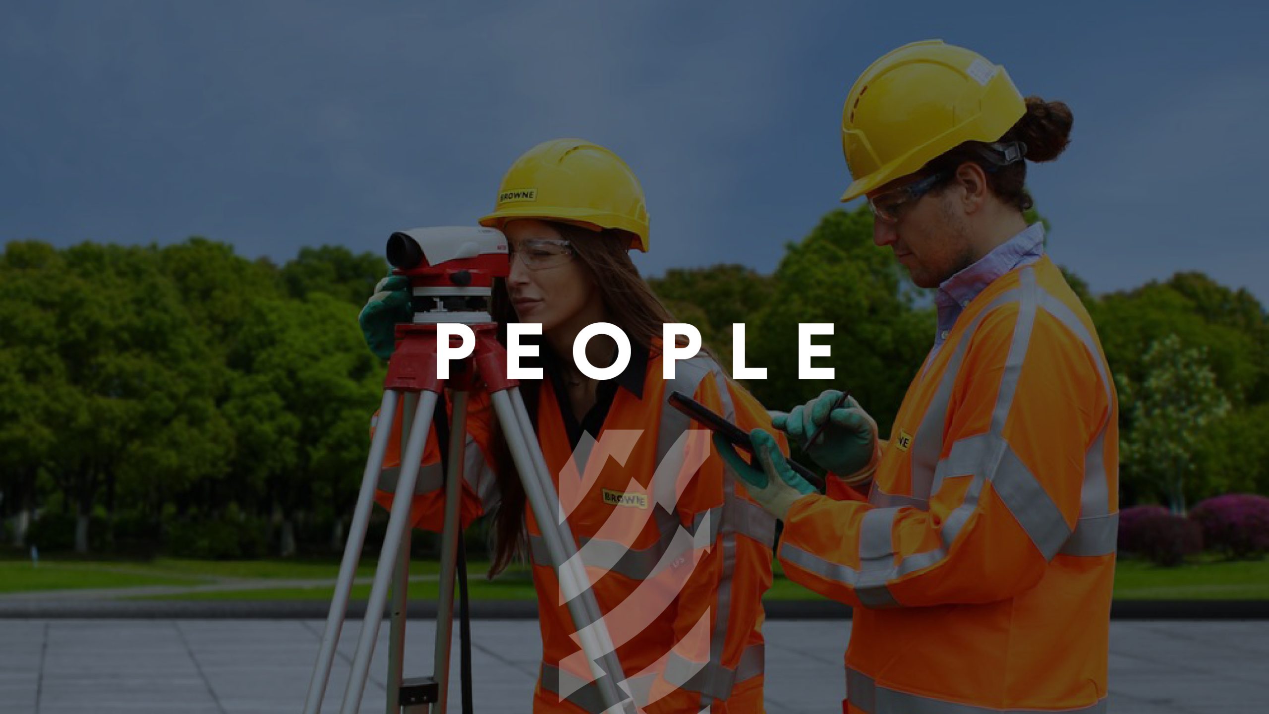 Browne Group - Two construction workers in safety gear using surveying equipment outdoors, with 