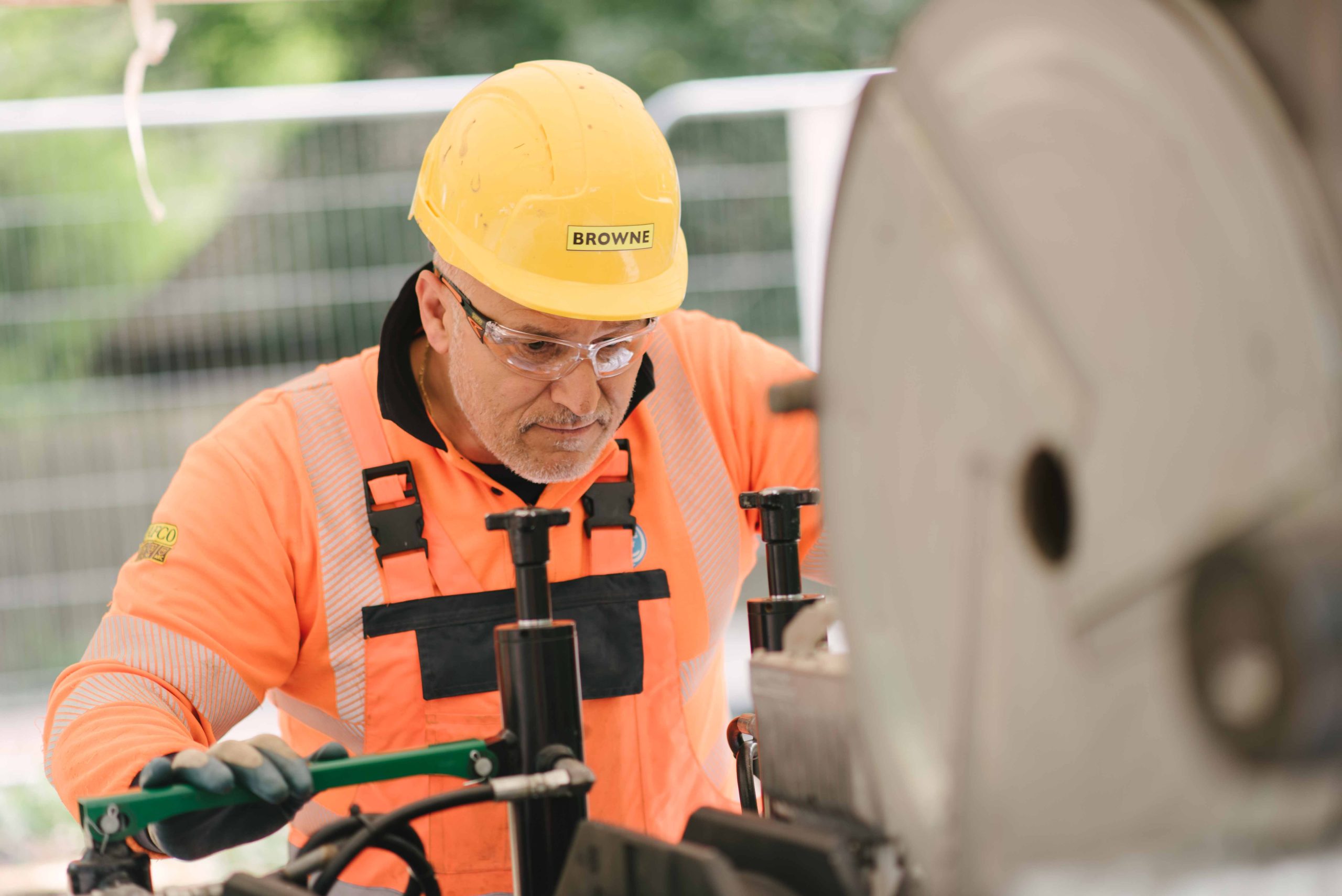 Browne Group - Construction worker in orange safety gear and helmet operating heavy machinery outdoors.