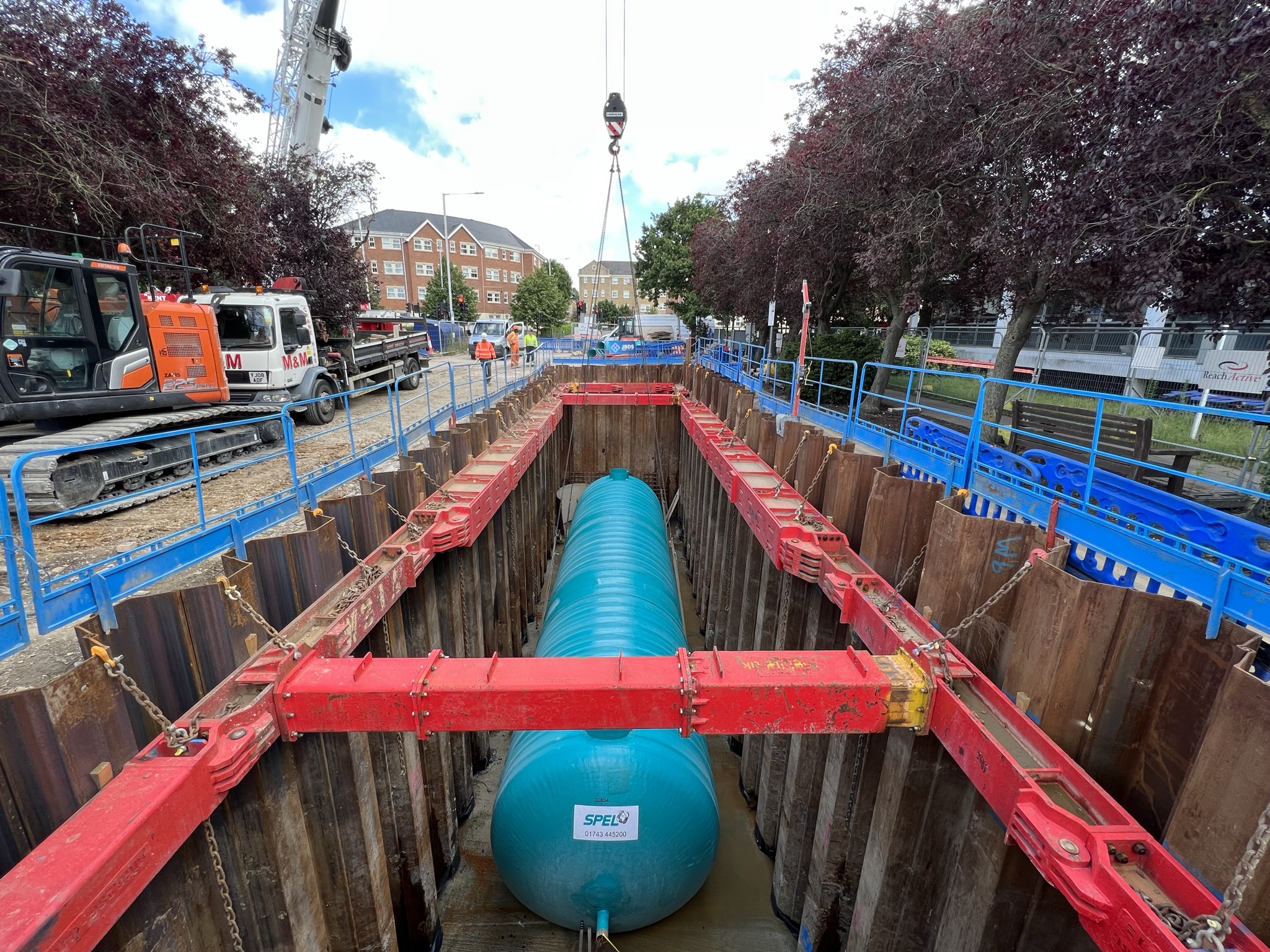 Browne Group - Construction site with large blue tank being installed in a deep trench, surrounded by safety barriers and machinery.
