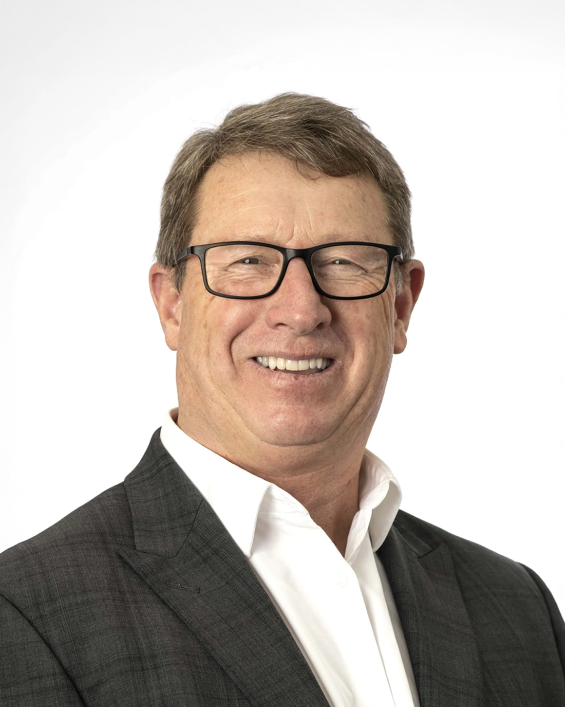 Browne Group - Smiling man in glasses, suit jacket, and white shirt against a plain white background.