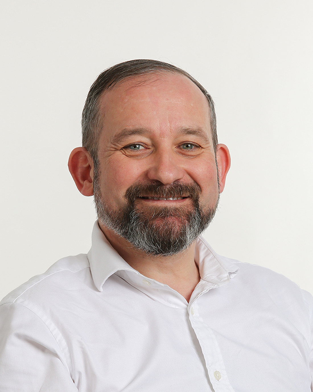 Browne Group - Smiling man with a beard in a white shirt, posing against a plain white background.