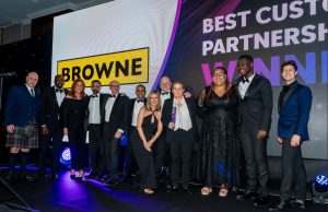 Browne Group - Group of people in formal attire posing on stage with a "BROWNE" sign and "BEST CUSTOMER PARTNERSHIP WINNER" in background.
