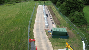 Browne Group - Aerial view of a row of industrial tanks on a temporary wooden path in a fenced field.