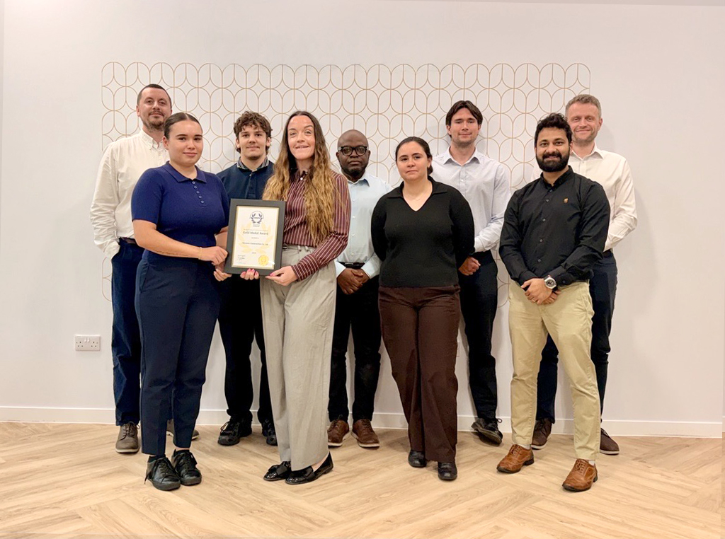 Browne Group - A diverse group of nine professionals standing together, with two women in the front center holding a Gold Medal award.
