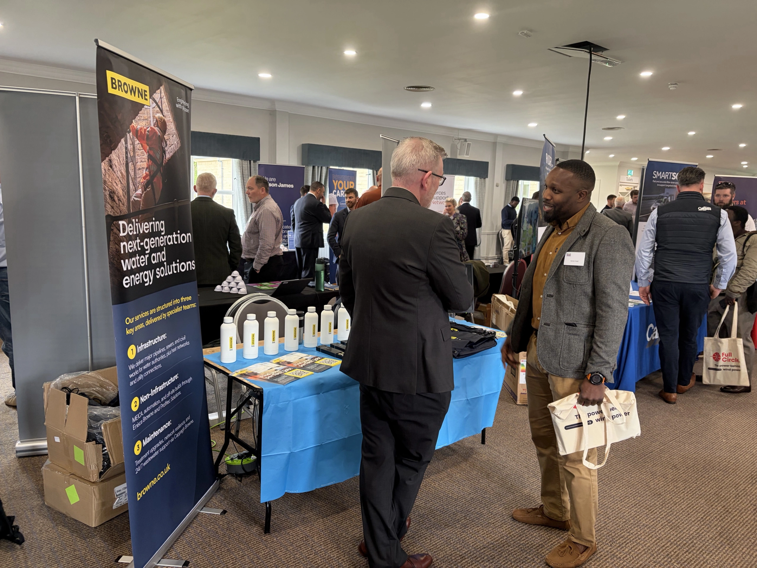 Browne Group - Two men talking at a corporate networking booth with a Browne company banner.